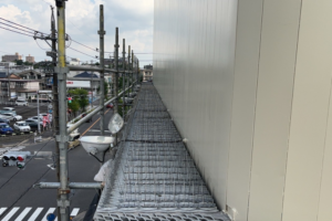 建物の外壁沿いに設置された足場通路。鳥の着地を防ぐための防鳥ピンが通路一面に隙間なく敷き詰められており、都市部での効果的な鳥害対策の様子を示しています。