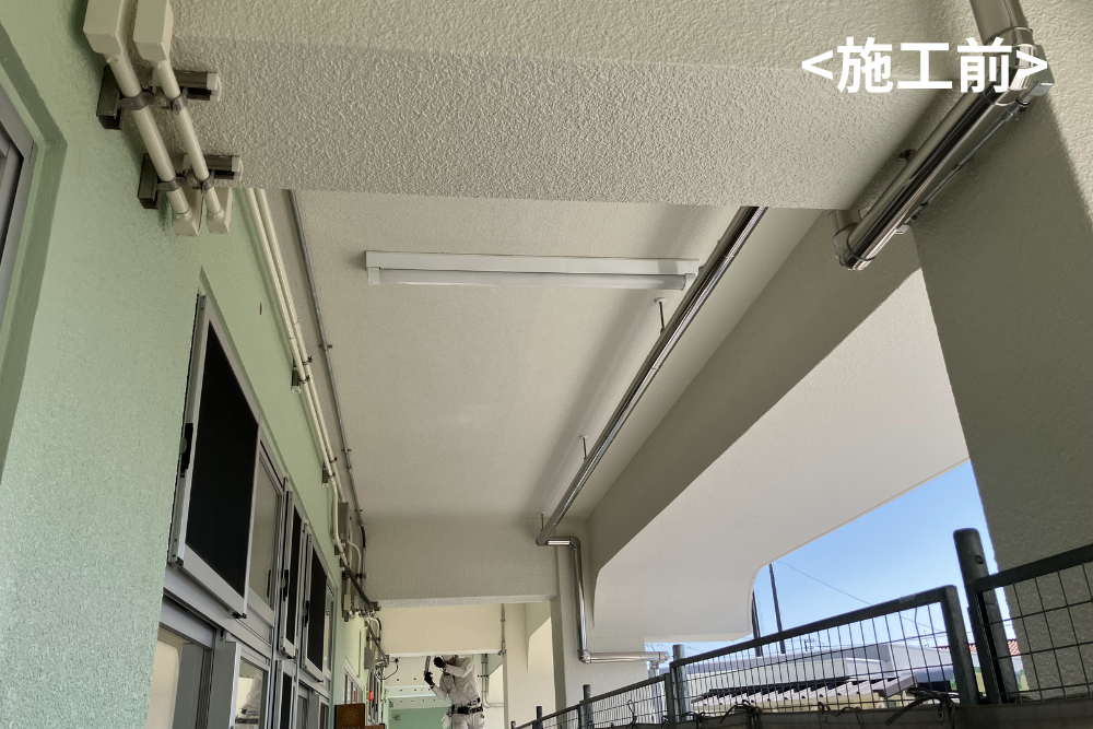 建物の屋外通路の天井に設置された、施工前の蛍光灯照明と配管の様子。