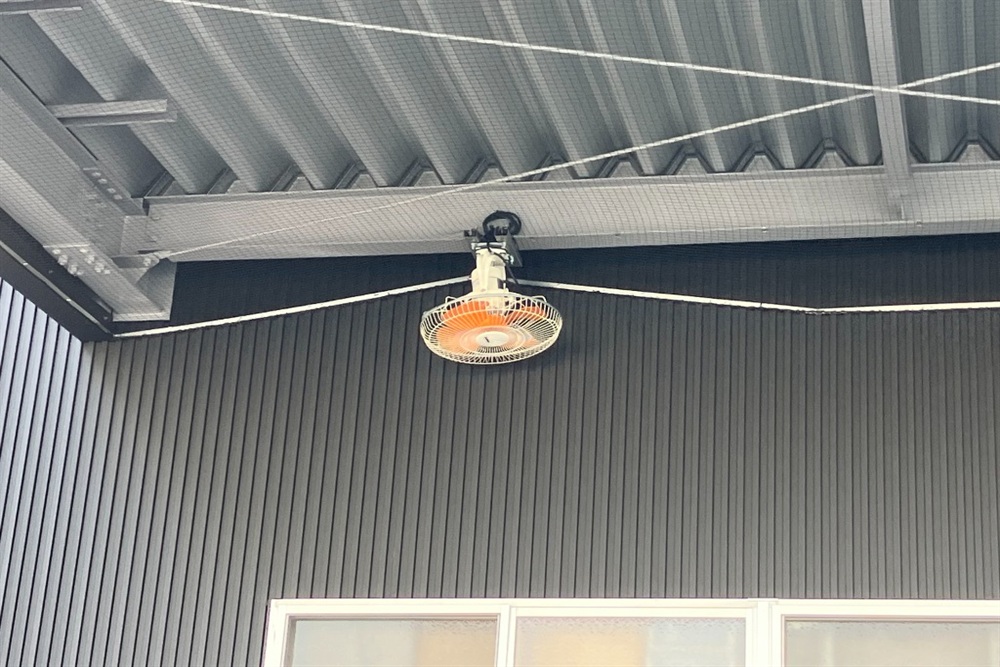 軒下にある壁掛け扇風機の上部、折板屋根の下に鳥が入り込まないよう、専用の防鳥ネットを設置した状態