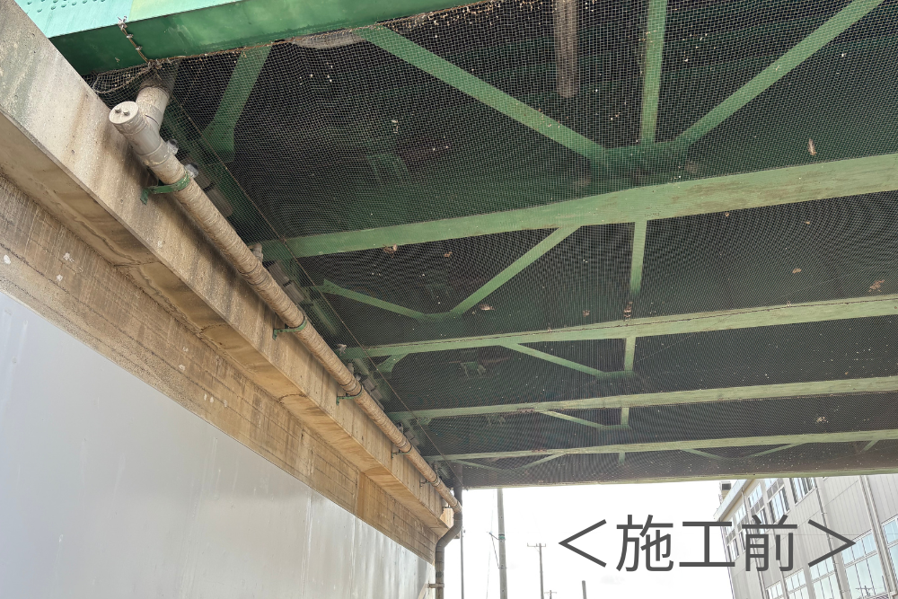 施工前の緑色の鉄橋下部の様子。古いネットにゴミが溜まり、鳥害対策の更新が必要な状態を示した画像です。