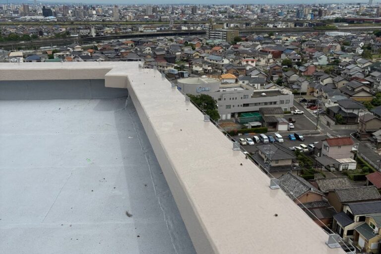 市街地と川を見渡すビル屋上の外周全体に張り巡らされた、防鳥ワイヤーの設置風景。景観を損なわずに広範囲の鳥害を防ぐ施工例です。